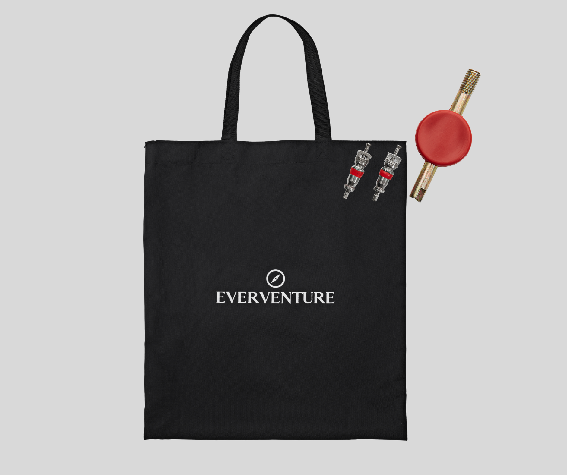 Black tote bag with 'EVERVENTURE' logo, two small figurines, and a red object on a light gray background